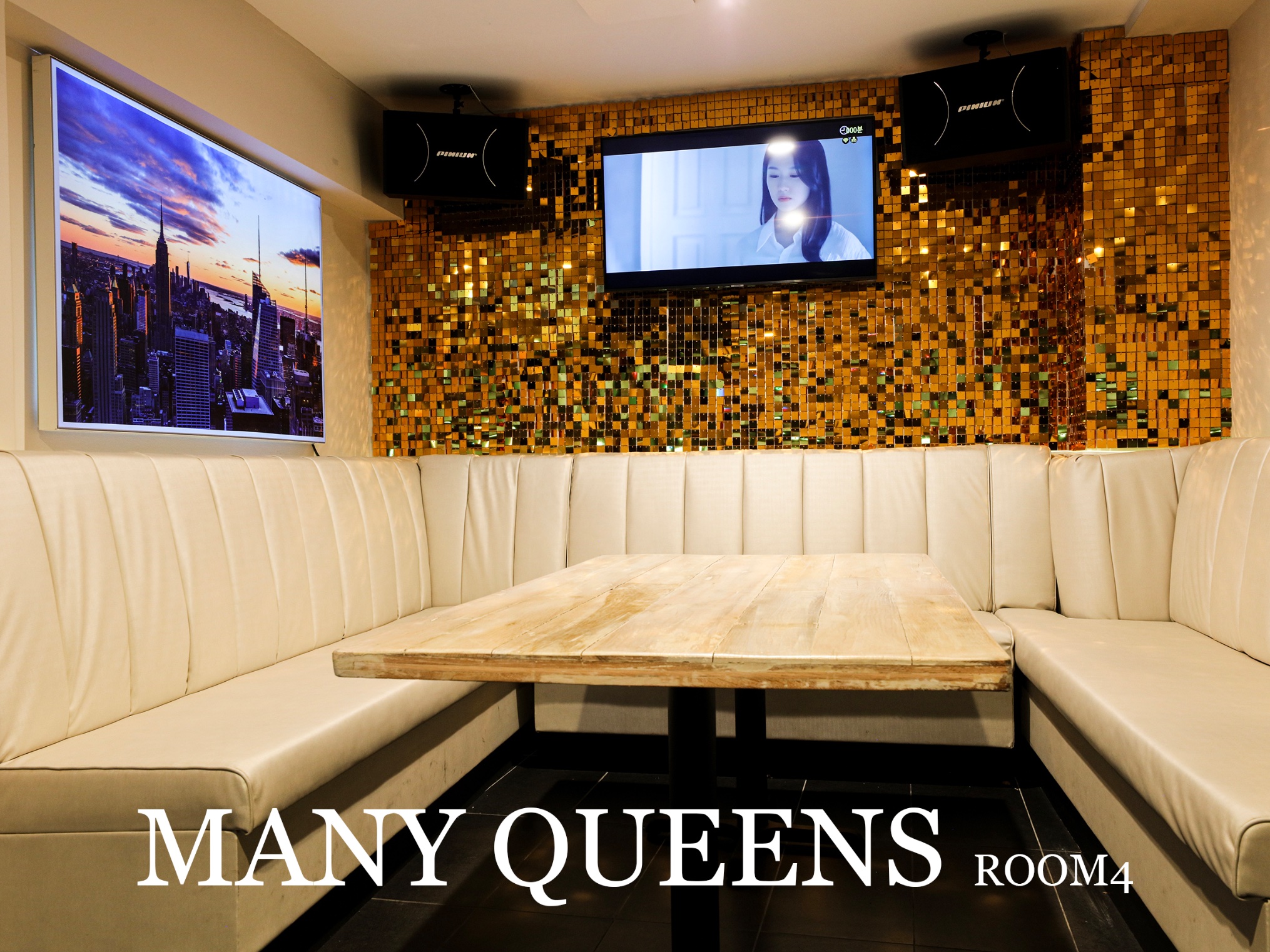 Private karaoke room with white lounge seating, marble table, and gold sequin wall